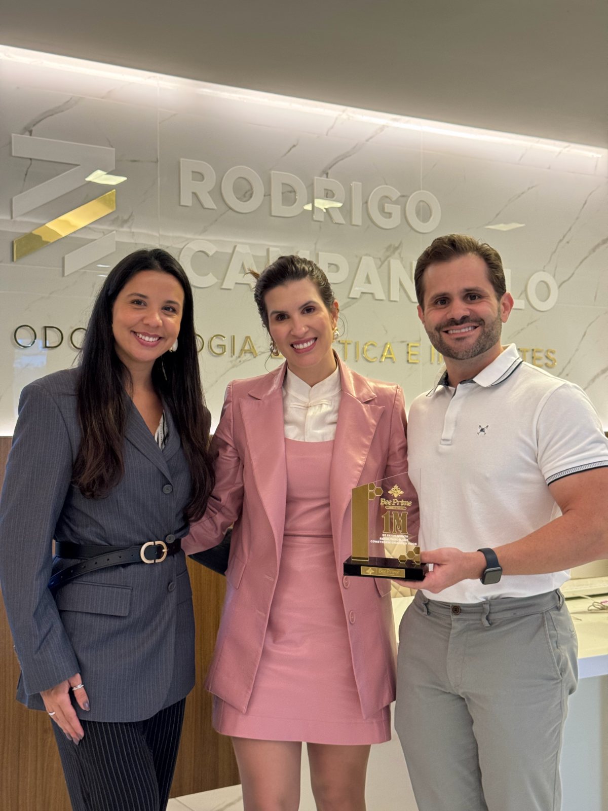 Equipe da clínica com a Brenna, segurando o troféu Bee Prime de 1 milhão de faturamento