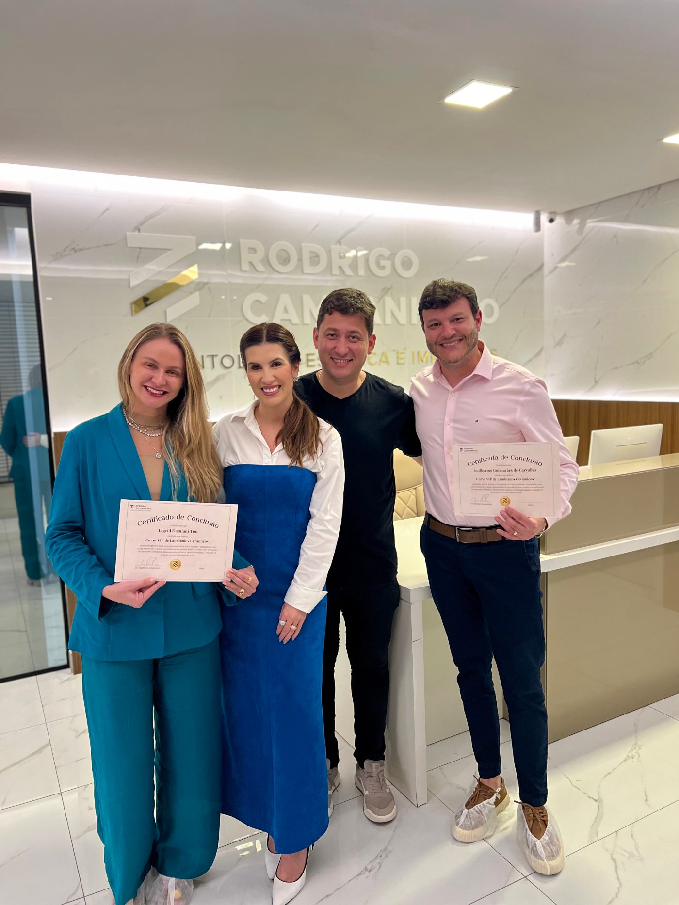 Dra. Ingrid e Dr. Guilherme com seus certificados, ao lado da Brenna e do Dr. Rodrigo, na recepção da clínica